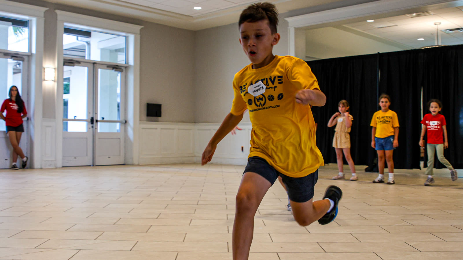 A boy sprinting across the gym at C+A BE ACTIVE summer camp